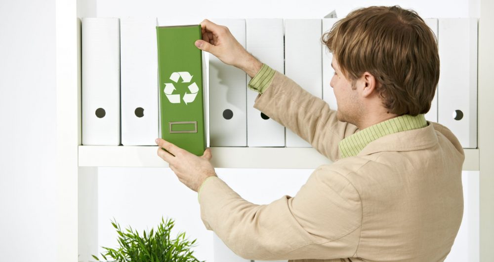 7129869 - man drawing out green folder with recycling symbol in office.