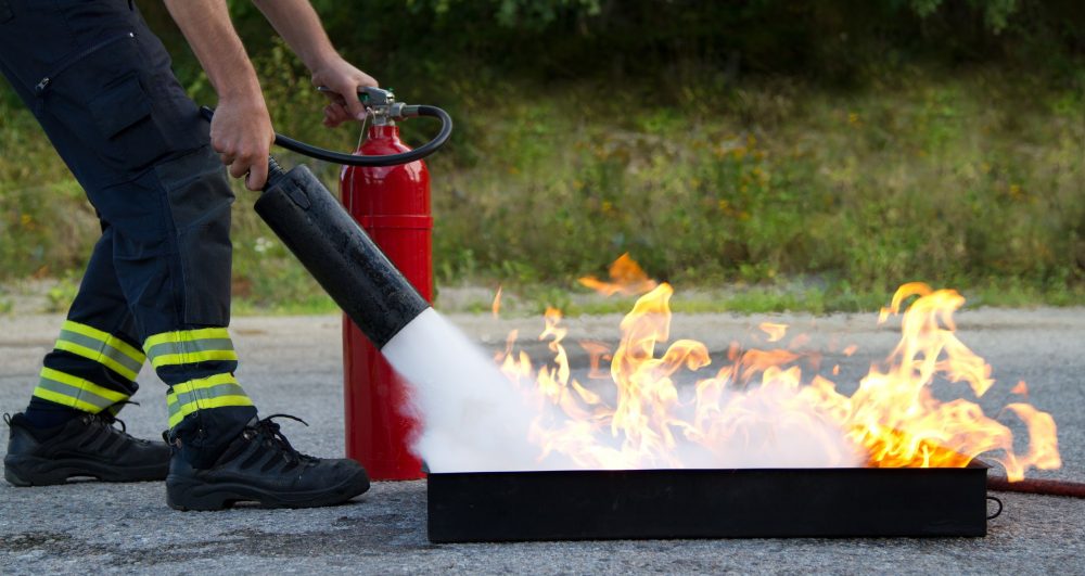 16872142 - instructor showing how to use a fire extinguisher on a training fire